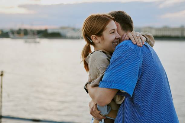 istock Embracing Couple Near Waterfront Scenery During Sunset 2174125179