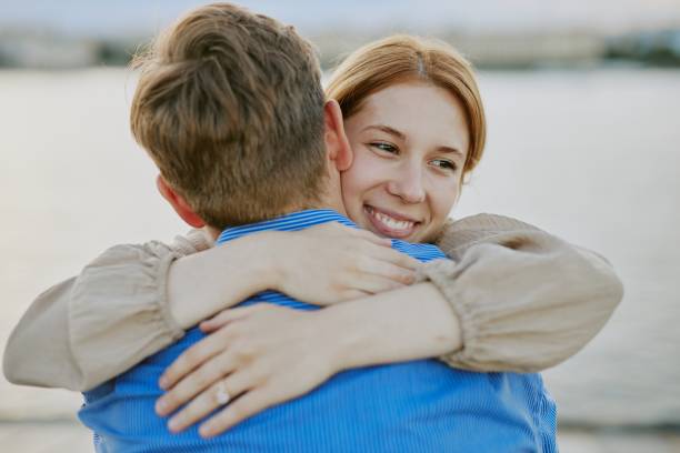 istock Smiling Woman Embracing Man Outdoors Near Water 2174125480
