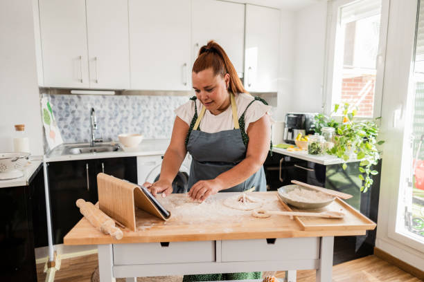 istock Woman following recipe on tablet while preparing dough in kitchen 2174128217