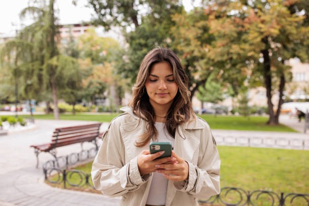 istock Young woman using her phone in a park 2174130158