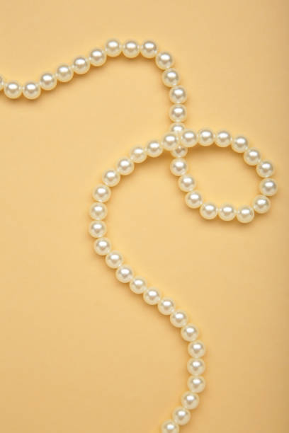 istock Elegant pearl necklace on beige background, top view. Space for text 2174131044