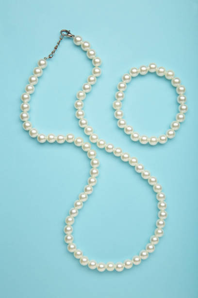 istock Elegant pearl necklace with bracelet on blue background, top view. Space for text 2174131068