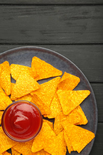 istock Nachos and ketchup on plate on black background. Mexican dish. Top view 2174131512
