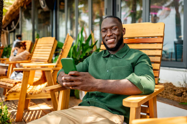 istock Smiling Man Relaxing Outdoors With Smartphone in Hand 2174132795