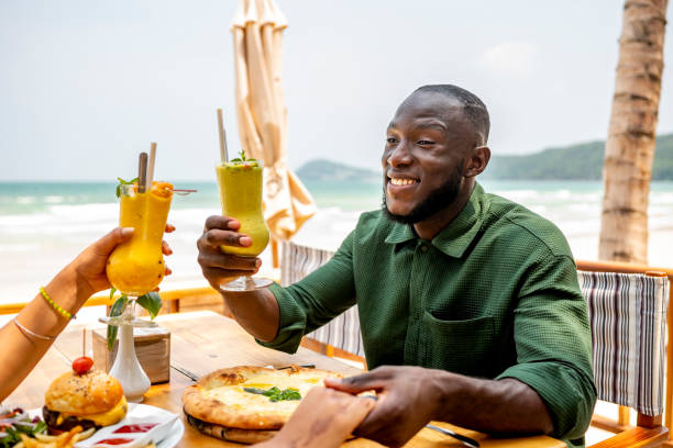 istock Man Enjoying Drinks and Pizza at Beachside Restaurant 2174132855