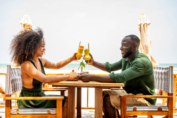 istock Happy Couple Toasting Drinks at Beachside Restaurant 2174132879