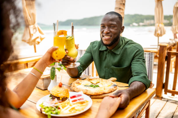 istock Happy Couple Enjoying Refreshing Drinks and Pizza at Beachside Cafe 2174132907