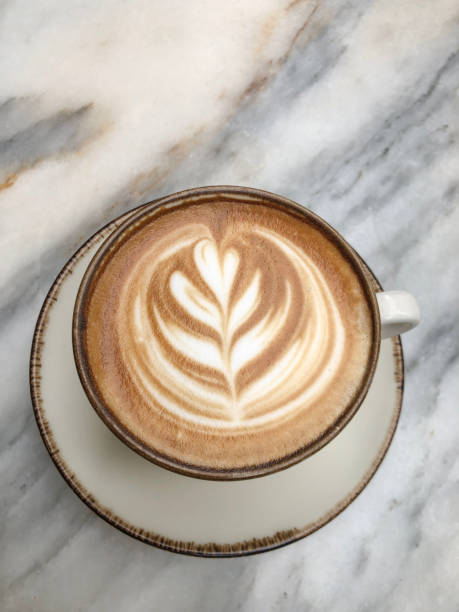 top view cup of cappuccino coffee with latte art on marble table