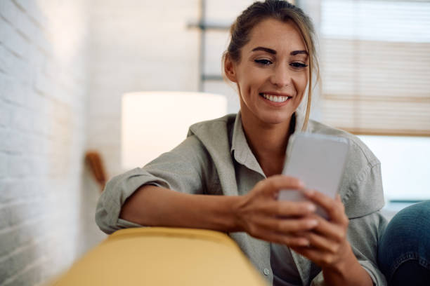 istock Young happy woman texting on cell phone at home. 2174136742