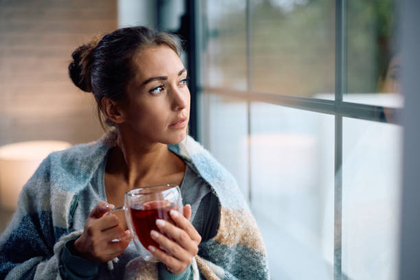 istock Young pensive woman drinking tea by the window. 2174137340