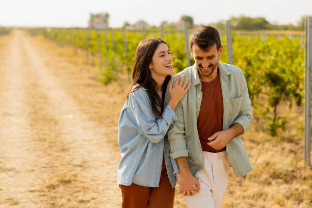 istock Couple strolls hand in hand along a sunlit path amidst lush vineyards during a warm afternoon 2174137566