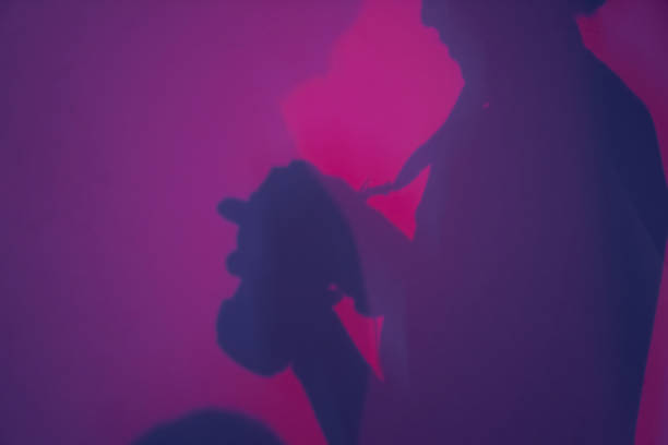 istock Background with a silhouette of a man with a camera, diffused light. Abstract gradient pink and purple background with the shadow of a woman photographer. 2174138309