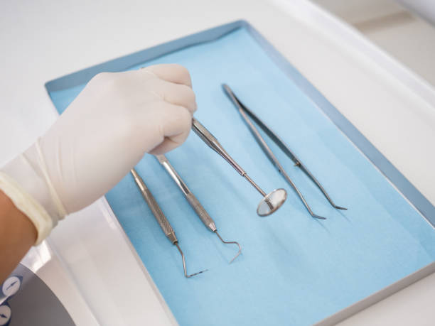 istock Hand of a dentist on a clinic taking a mirror between other tools at a tray 2174141211