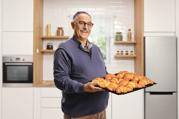 istock Mature man holding a tray with croissants 2174141988