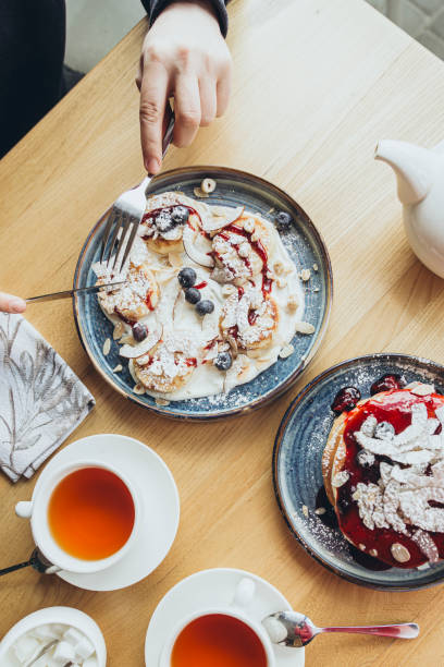 istock A man eats sweet cheesecakes for breakfast in a cafe, top view. 2174143609