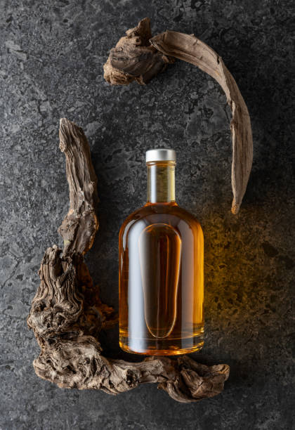 istock Bottle of whiskey and old snags on a black stone background. 2174145186