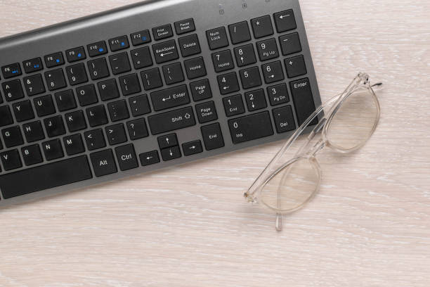 istock Black Keyboard and Round Glasses on Light Wooden Desk - Office Work Workspace Essentials 2174145193