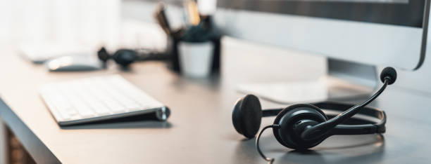 istock Panorama view of empty call center operator workspace focus on headset. Prodigy 2174146238