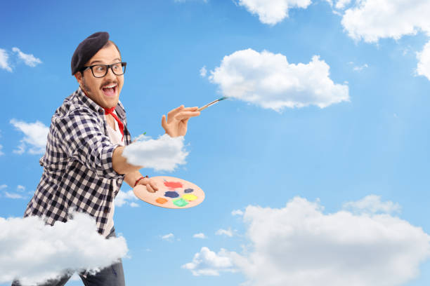 Excited male artist painting clouds in the sky