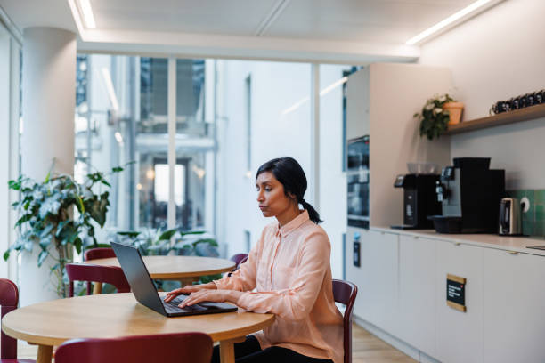 istock Professional Hispanic Woman Working on Laptop in Office Cafeteria 2174150413