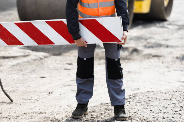 istock Construction worker in high-visibility vest handling a safety barrier during roadwork on a sunny day at a construction site 2174156054