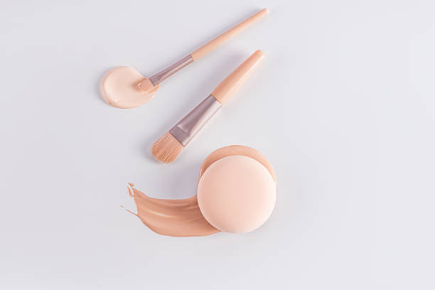 istock Delicate cosmetic background in light colors with two makeup brushes, a round sponge on a sample of foundation liquid powder. top view. A copy space 2174156686