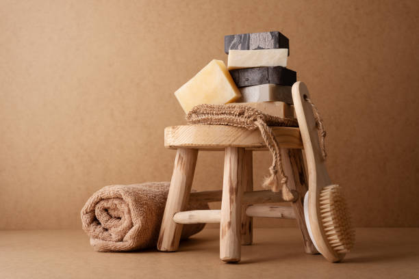 istock A stack of natural handmade soap bars with a wooden back brush and rolled towel on a rustic wooden stool 2174156762