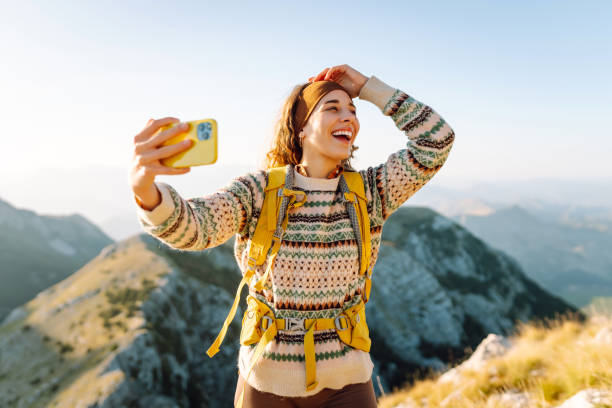 istock Young woman enjoying a hiking adventure while taking a selfie on a mountain summit during a sunny day. 2174157532