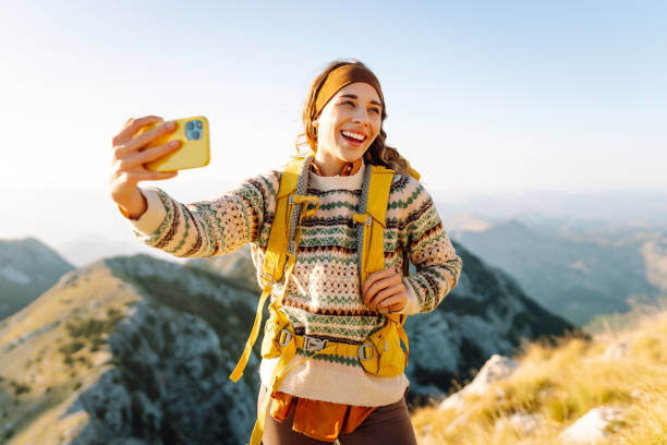 istock Young woman enjoying a hiking adventure while taking a selfie on a mountain summit during a sunny day. 2174157535