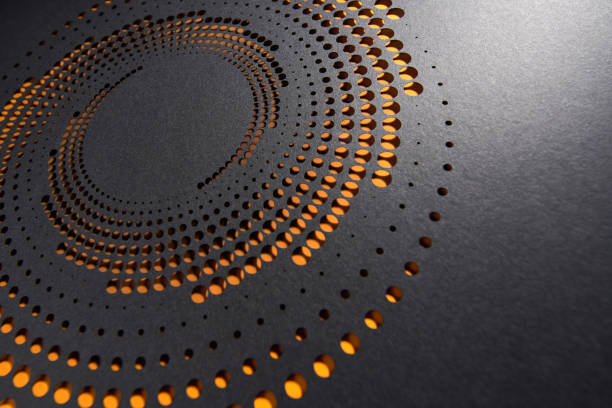 istock Intricate cut paper design with circular perforations and warm orange tones on a dark gray surface 2174159367