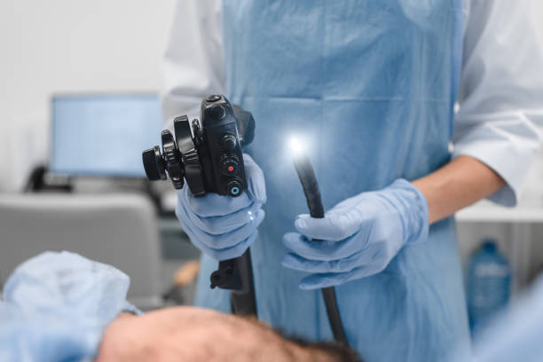 Gastrointestinal fiberoptic endoscopy concept. Cropped close up shot of female doctor holding modern endoscope device before gastroscopy examination with blue protective gloves stock photo