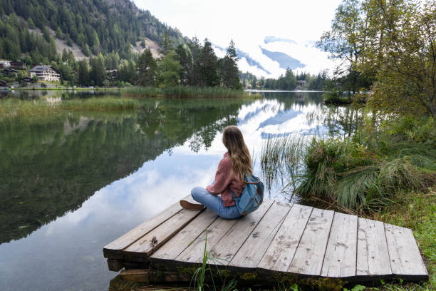 istock Woman Relaxing by a Tranquil Mountain Lake 2174168936