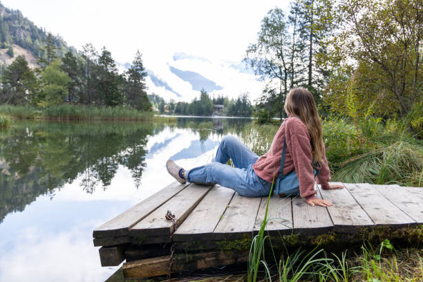 istock Woman Relaxing by Tranquil Mountain Lake 2174168962