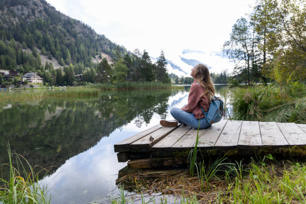 istock Woman Relaxing by a Tranquil Mountain Lake 2174168964