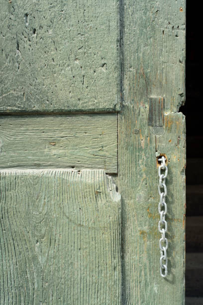 Weathered black wooden door showing a heavy metal chain and padlock