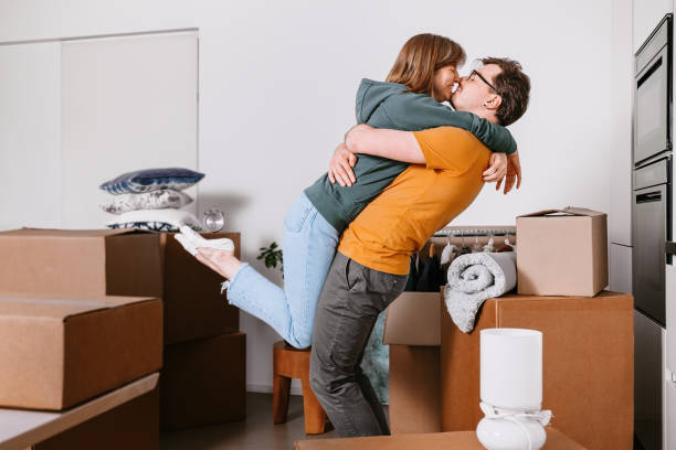 istock Couple Playfully Celebrate Moving Around Moving Unpacked Boxes 2174172511