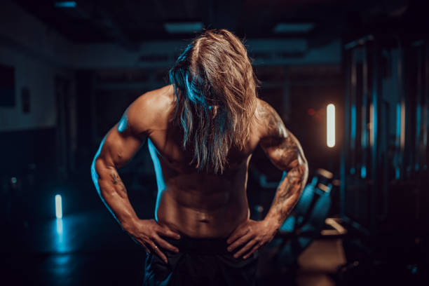 istock Bodybuilder with long hair and tattoos under blue lights 2174172850