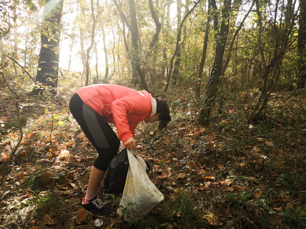 istock Woman picking up trash in the forest on a sunny day 2174175549