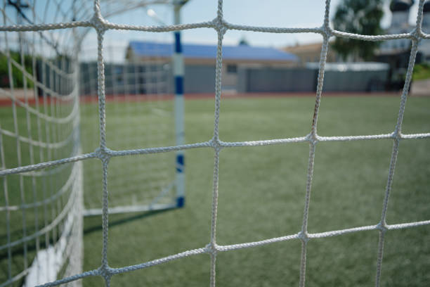 net of football goal, green artificial grass, football field, sunny summer day, selective focus