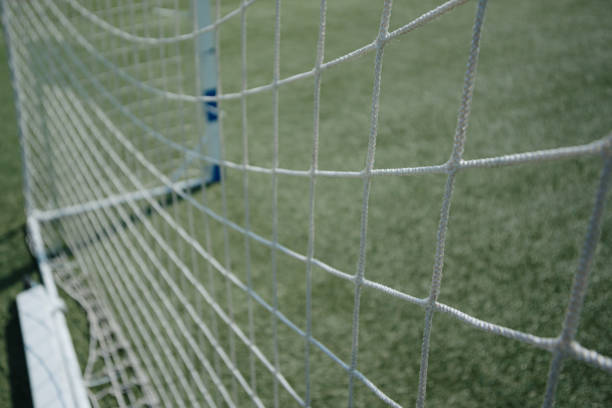 net of football goal, green artificial grass, football field, sunny summer day, selective focus