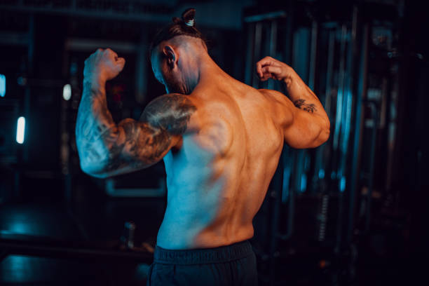 istock Muscular man flexing muscles in the dark gym room 2174178311