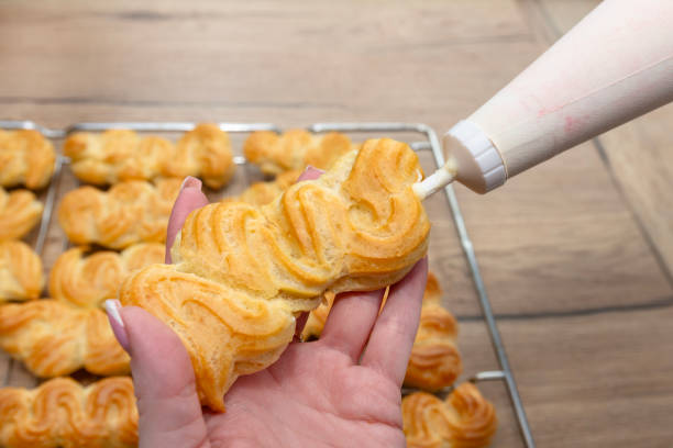 istock A woman fills eclairs with custard mass using a pastry bag. 2174187111