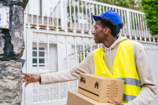 istock Young African courier pressing doorbell while holding packages, working in urban area 2174189108