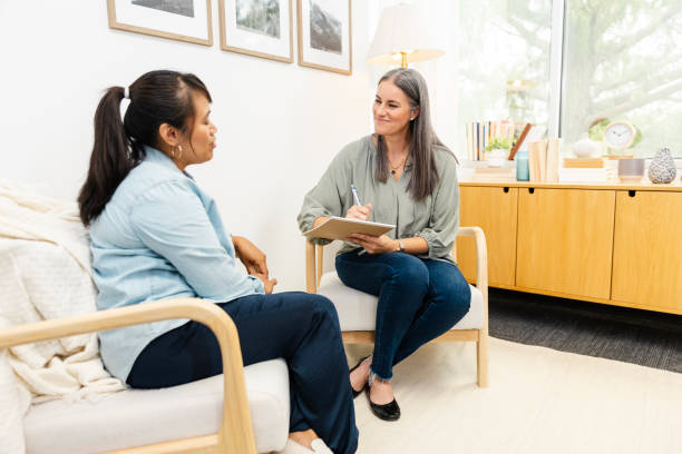 istock Mature female counselor grins while listening to her client talk 2174191946