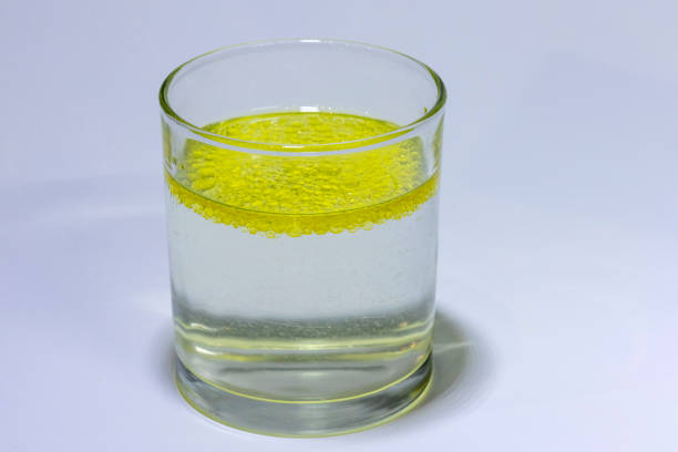 Oil mixed in a glass with water showing that the water and oil separate with the oil floating to the top
