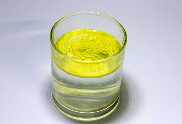 Oil mixed in a glass with water showing that the water and oil separate with the oil floating to the top