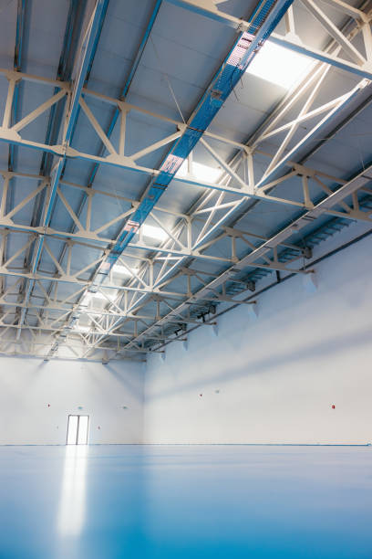 istock Empty sports hall with blue floor reflecting light from ceiling windows 2174200198