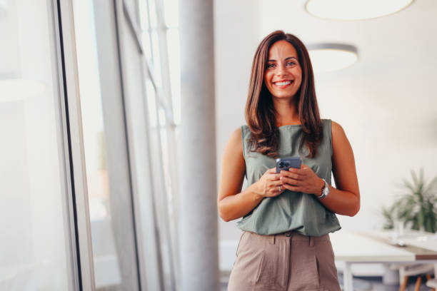 istock Smiling businesswoman using phone in office 2174201274