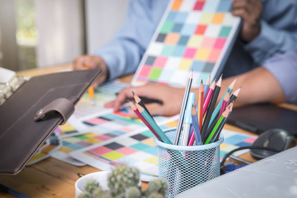istock Several pencils in a pencil case over clothing designers working in background. 2174202868