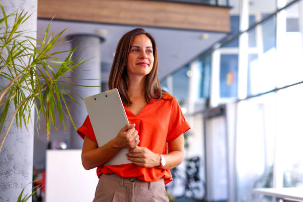 istock Smiling businesswoman standing in office with clipboard 2174203036